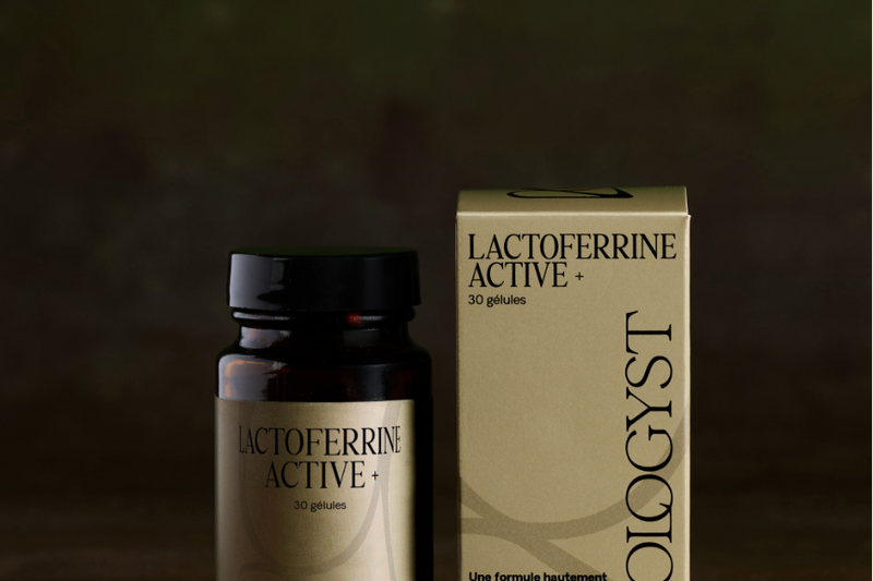 Flacon et étui Lactoferrine Active+ de Biologyst, deux gélules posées sur une table en bois