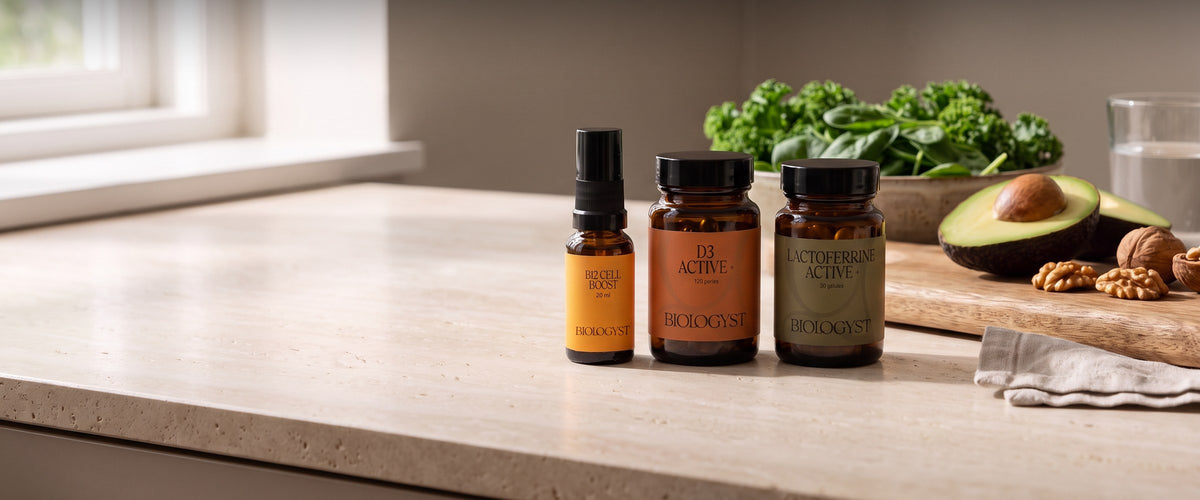 B12 Cell Boost, D3 Active+ et Lactoferrine Active+ sur un plan de travail en travertin, avec des légumes verts, un avocat et des noix, dans la lumière du matin